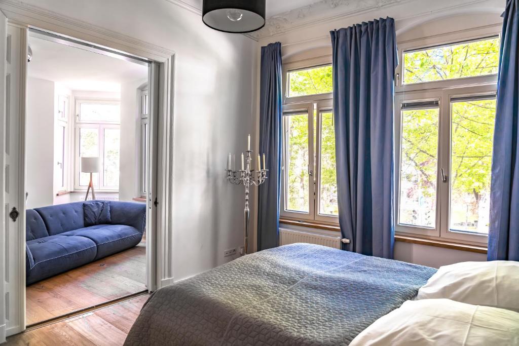 ein Schlafzimmer mit einem blauen Bett und einem blauen Sofa in der Unterkunft Modernes City-Apartment mit Blick in den Park und 2 Bäder H9 in Oldenburg