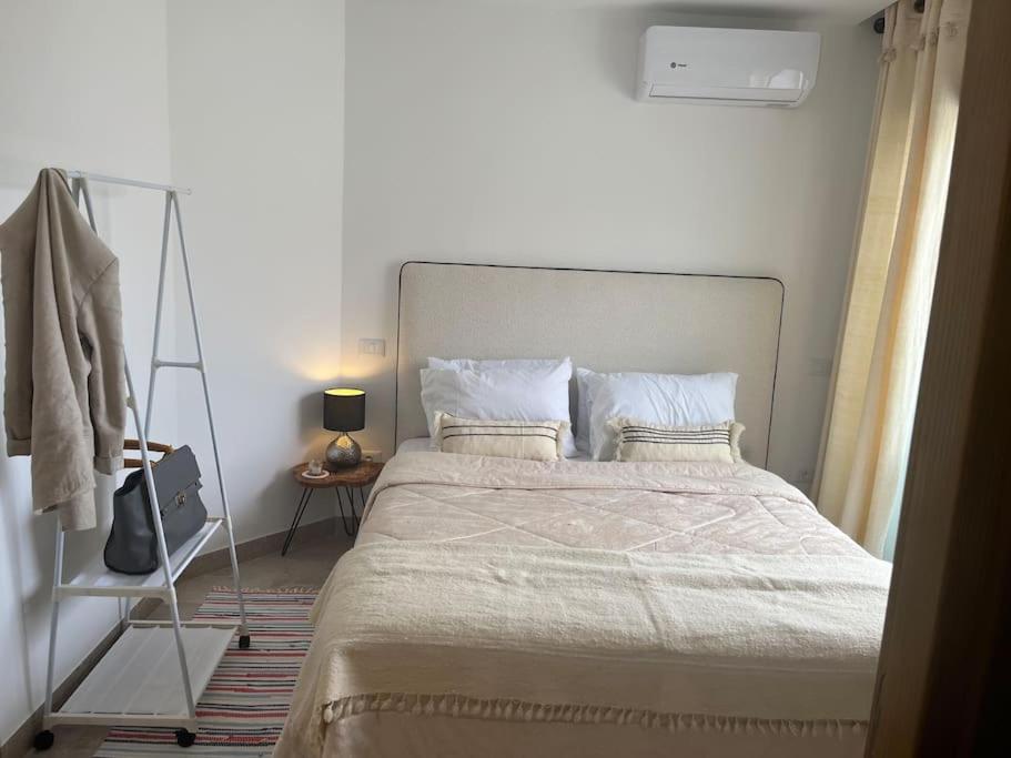 a bedroom with a large bed and a clothes rack at Appartement avec piscine et 10 min plage in Hammamet Nord