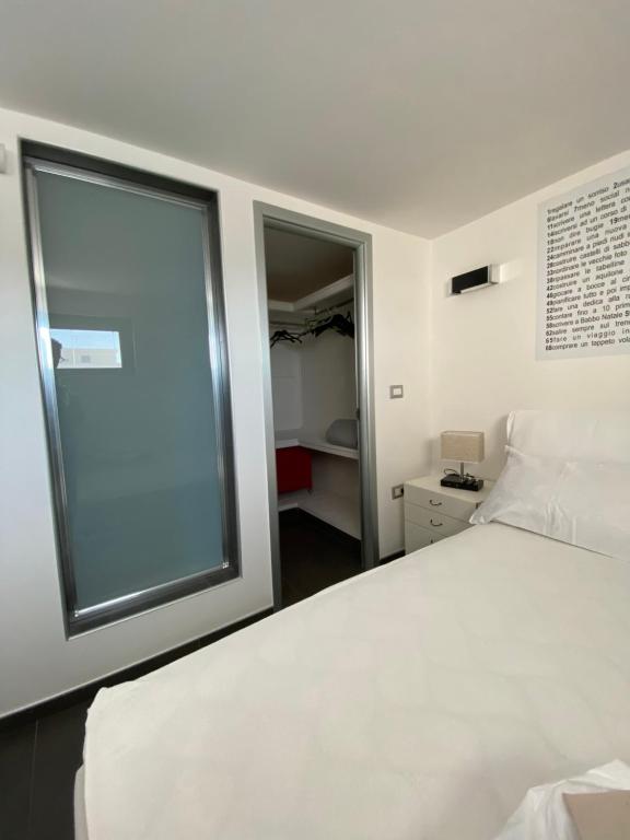 ein Schlafzimmer mit einem weißen Bett und einem großen Fenster in der Unterkunft Attico Tra Cielo e Mare in Margherita di Savoia