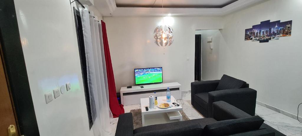 a living room with two chairs and a television at Appartement meublé grand luxe à Essos in Yaoundé