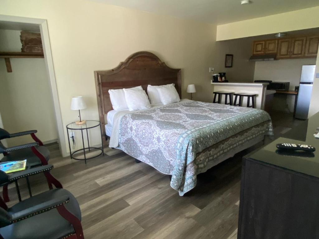 a bedroom with a large bed and a kitchen at Bishop Village Motel in Bishop