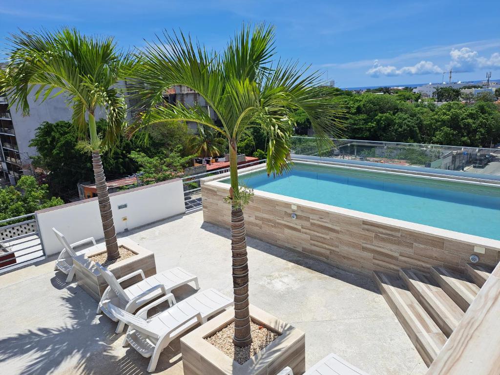dos palmeras y una piscina en un edificio en Condo Kiaraluna en Playa del Carmen