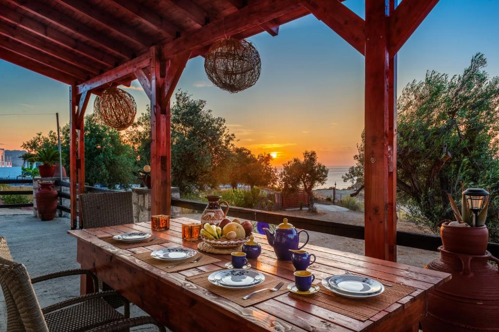 un tavolo in legno con un cesto di frutta e un tramonto di Blue Bay Villas , Ground Floor a Archangelos