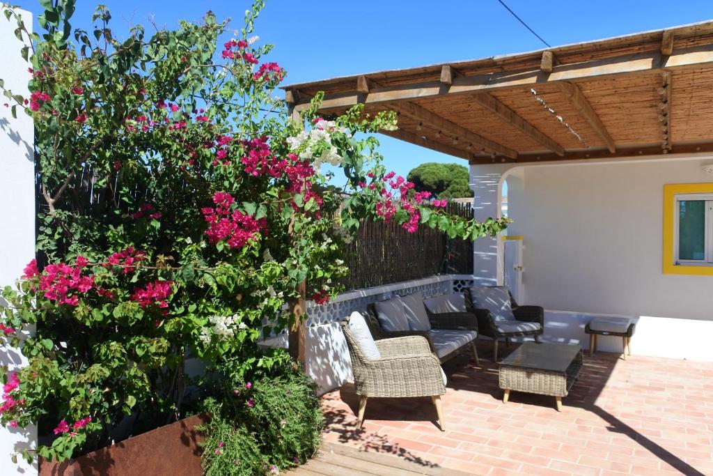 eine Terrasse mit Blumen, einem Sofa und Stühlen in der Unterkunft Casa do Livramento in Luz de Tavira