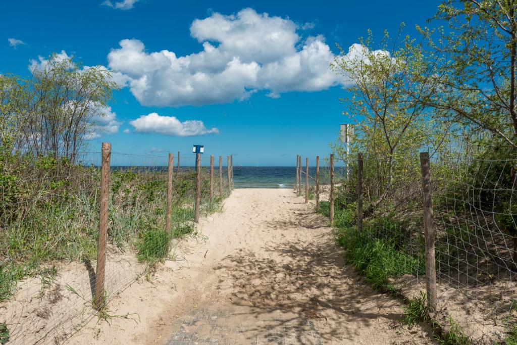 un camino de tierra a la playa con una valla en Apartamenty Apartinfo - Blue Side Family, en Gdansk