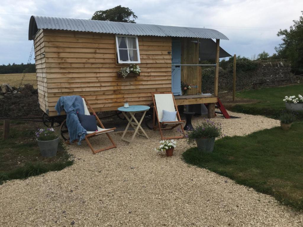 una casa pequeña con una mesa y sillas delante en Dolly’s shepherds hut, en Trowbridge