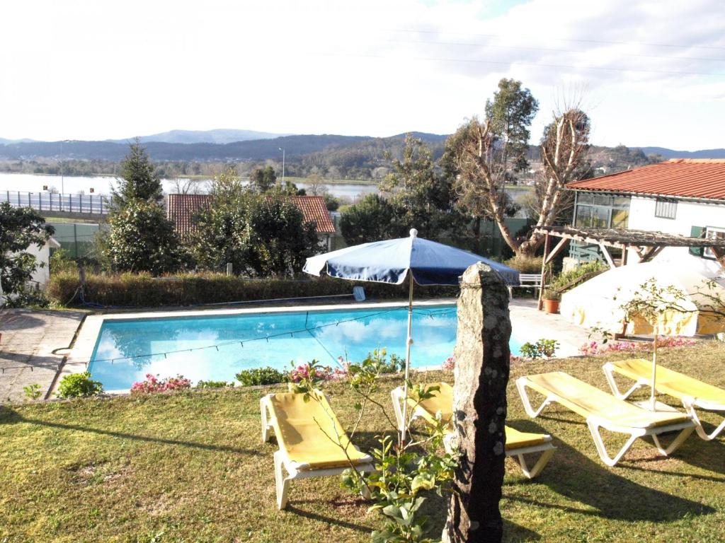 een zwembad met 2 ligstoelen en een parasol bij VNC13V4, encantadora casa e piscina, vista rio Min in Gondarém