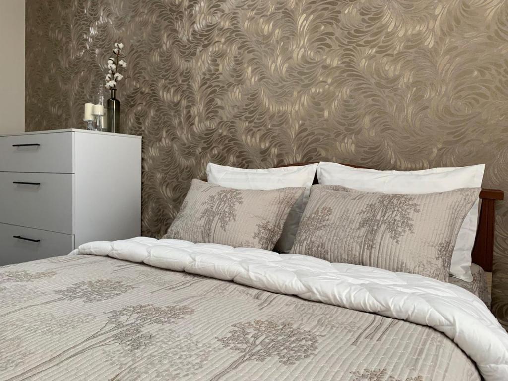 ein Schlafzimmer mit einem weißen Bett mit Kissen und einer Wand in der Unterkunft Apartment Guli in Taschkent