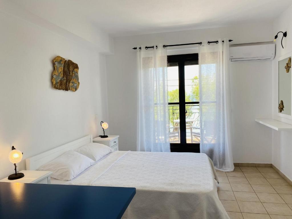 a white bedroom with a bed and a window at Harmony Seaside Pelion in Platanias