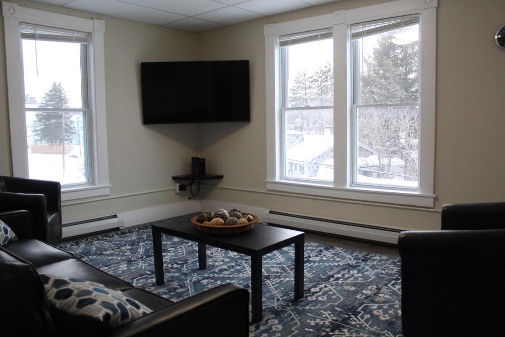 a living room with a couch and a table and windows at Fabulous Barre Apts! in Barre