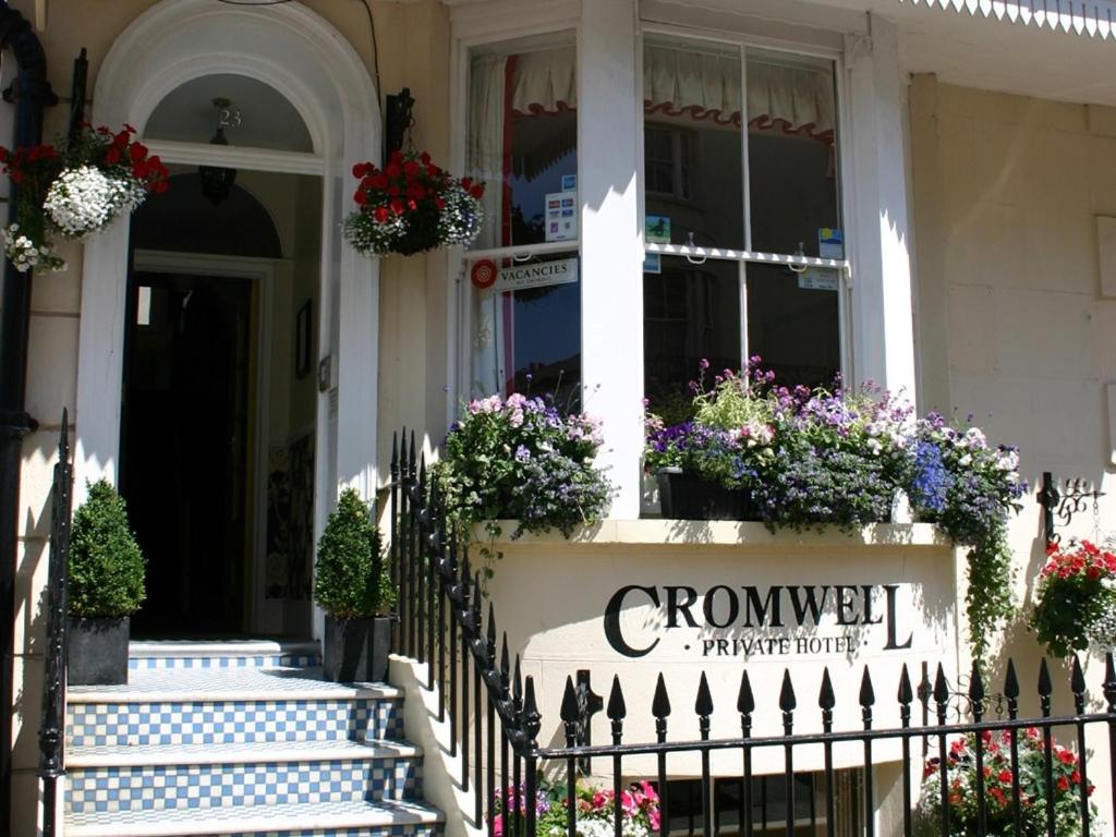 ein Schild an der Vorderseite eines Hauses mit Blumen in der Unterkunft Cromwell House in Eastbourne