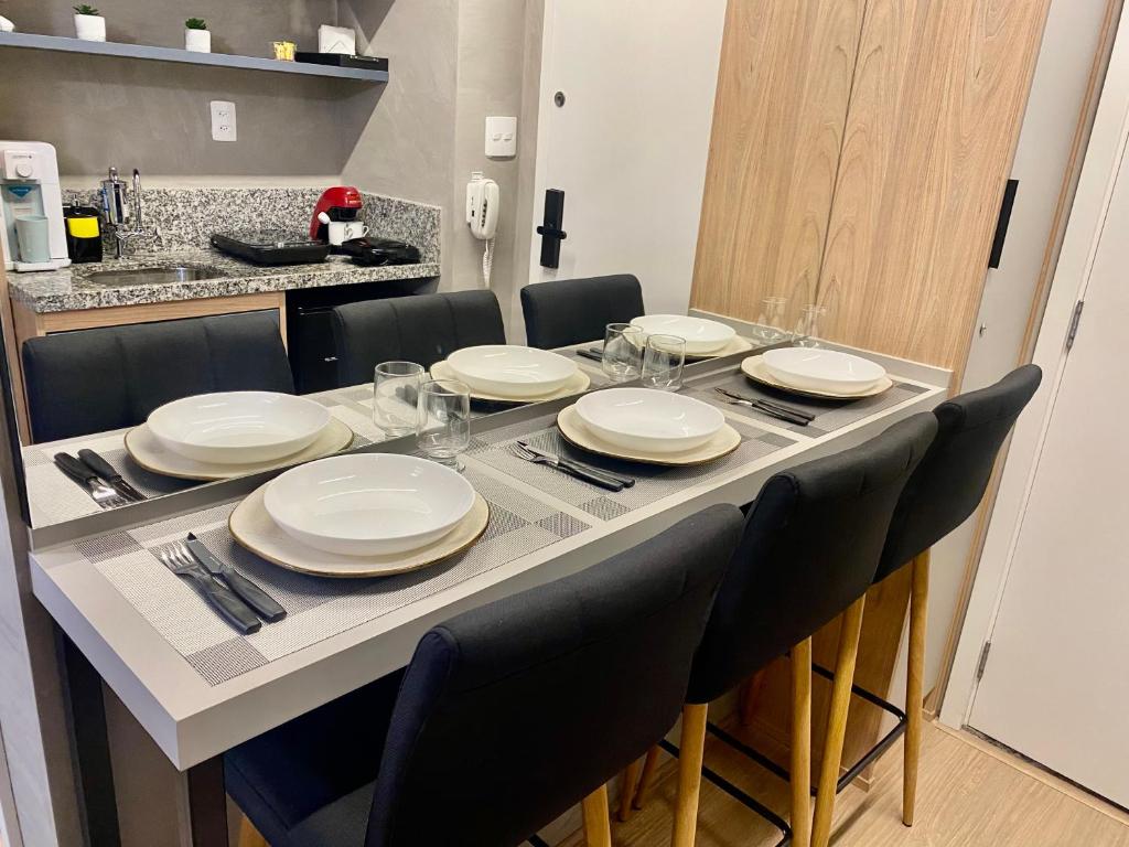a dining room table with chairs and plates on it at Lindo Apartamento Em Frente Ao Metrô Brás ! in São Paulo