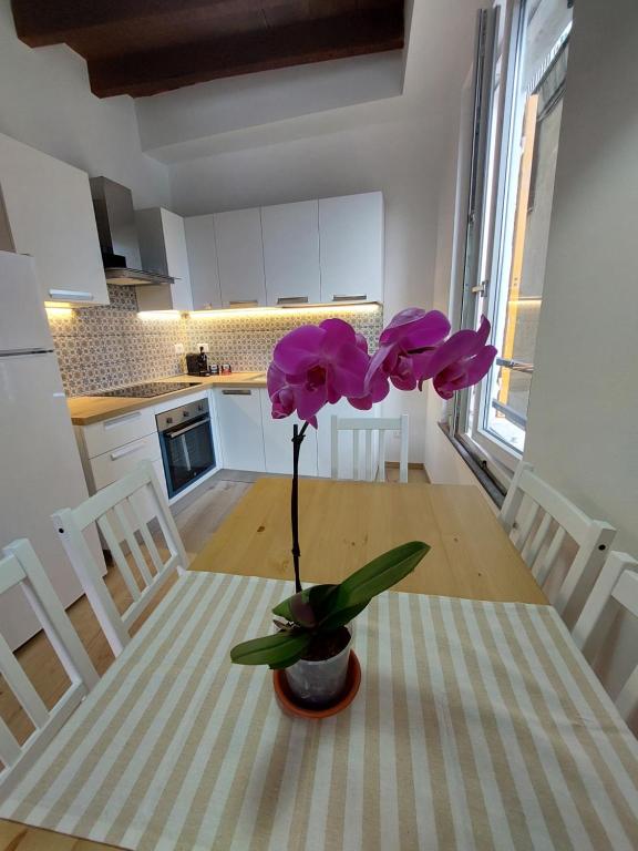 wazon z fioletowymi kwiatami na stole w kuchni w obiekcie DA me MAE w mieście La Spezia