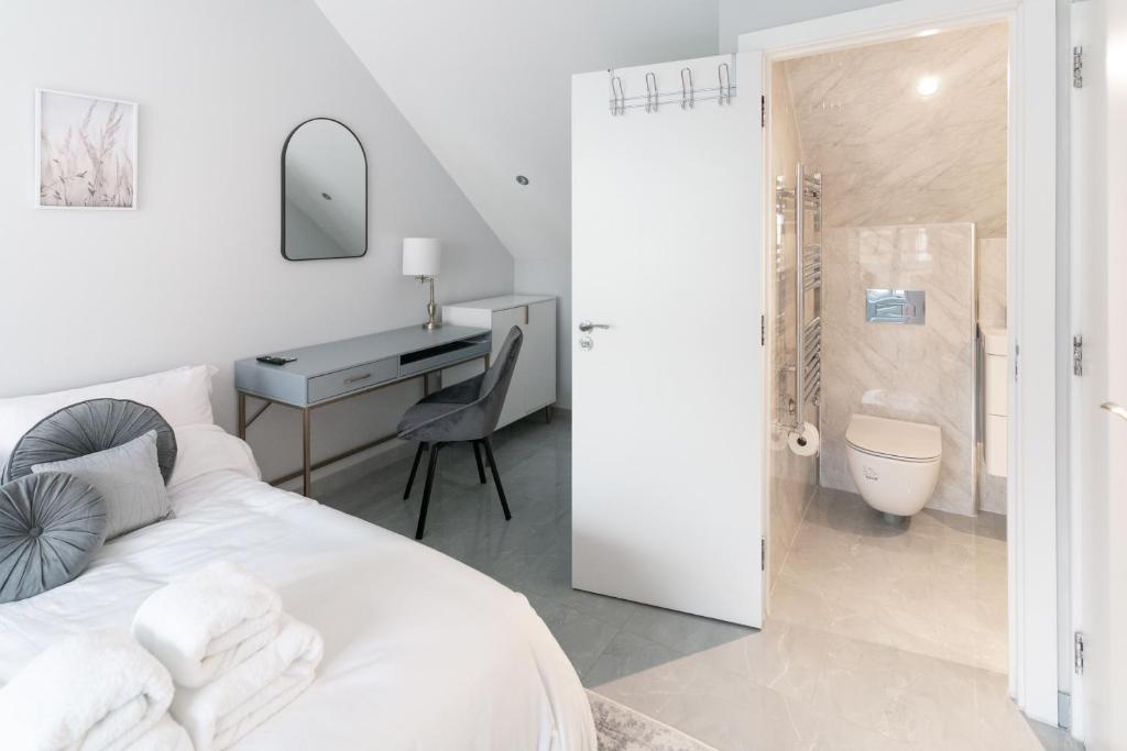 a bedroom with a bed and a desk and a bathroom at Luxury 5BD Suite Guest House in London