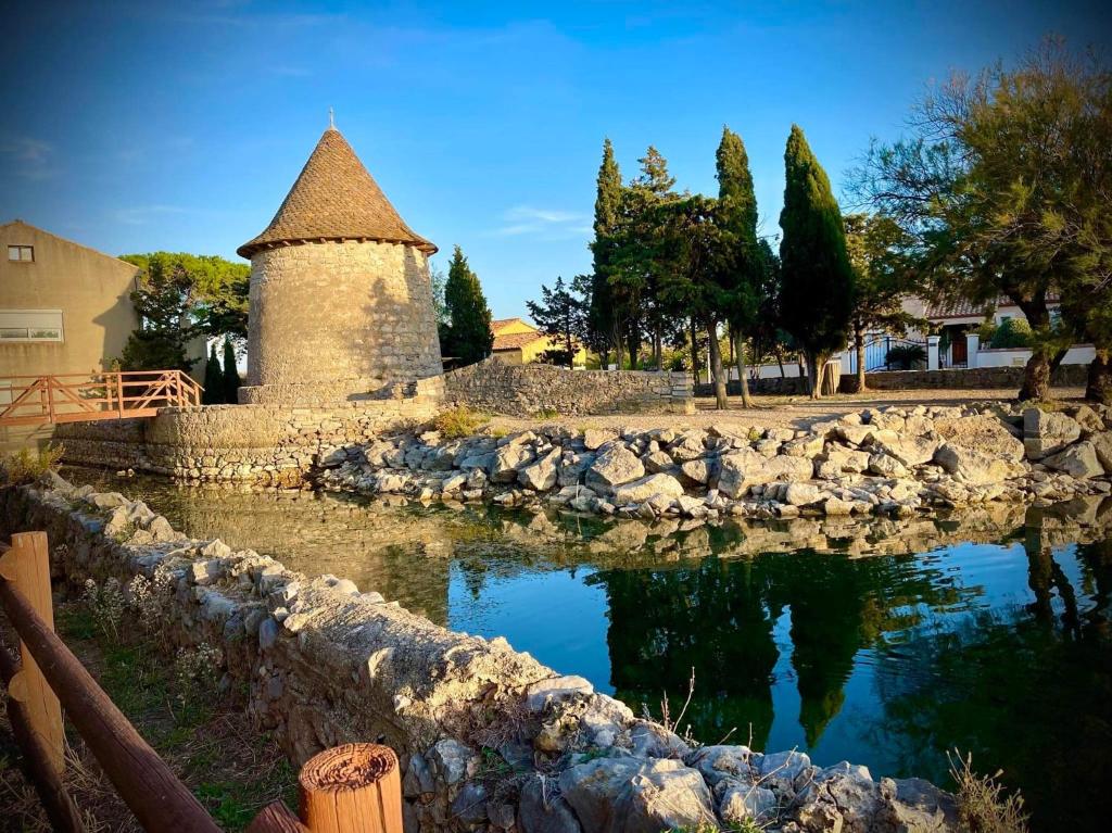 a stone wall with a pond in front of a building at Duplex proche mer, avec swimspa terrasse, jardin et barbecue in Lapalme