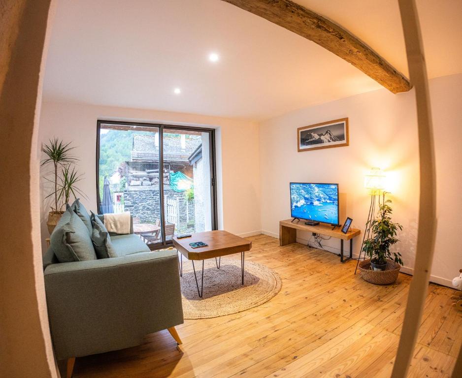 un salon avec un canapé et une télévision dans l'établissement Maison de Vacances à la montagne, à Laruns