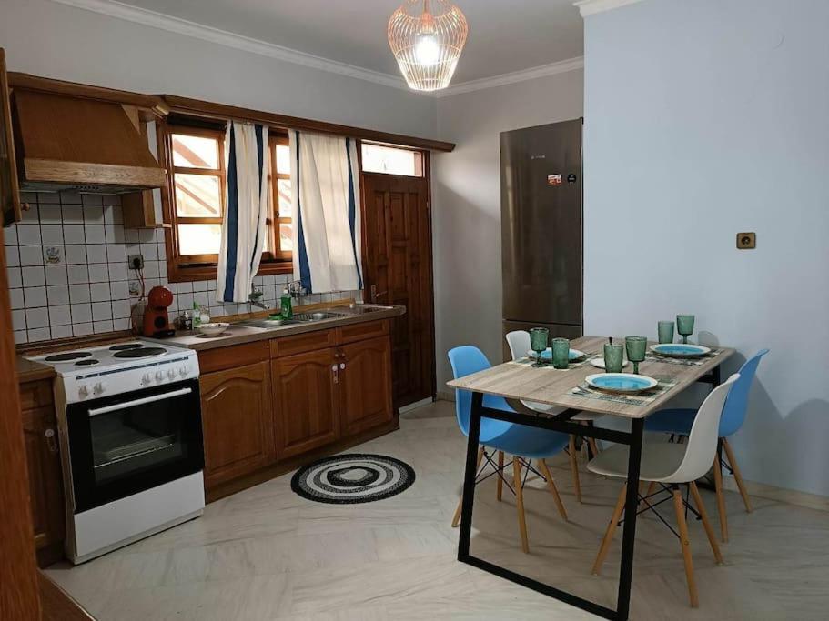a kitchen with a table with blue chairs and a stove at Perivolia Serenity in Chania in Ayiá