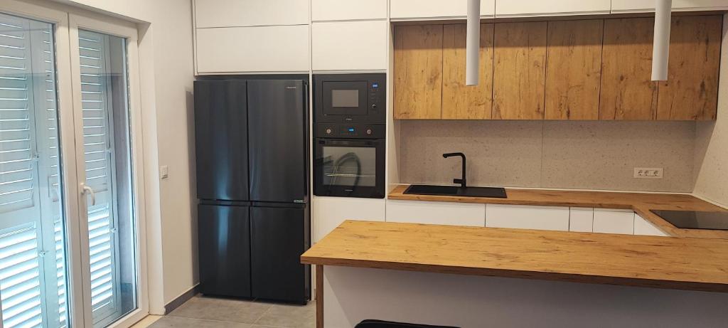 a kitchen with a black refrigerator and a counter at Vila Bartulović in Kučiće