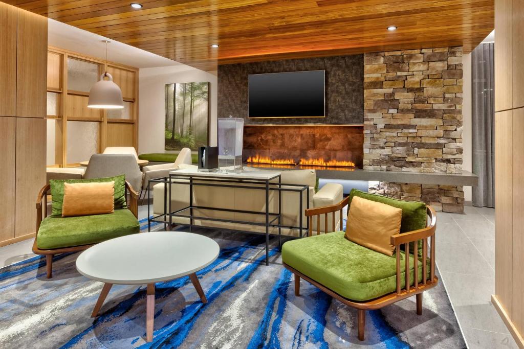 a living room with a fireplace and green chairs at Fairfield by Marriott Inn & Suites Knoxville Airport Alcoa in Alcoa