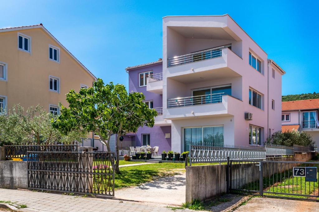 une maison rose avec une clôture devant elle dans l'établissement KAIROS, à Bilice