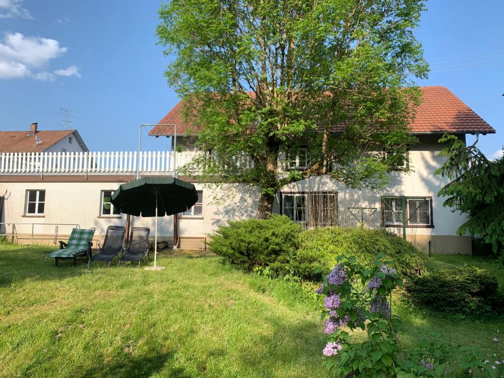 uma casa com duas cadeiras e um guarda-sol no quintal em Wohnung mit Garten, Grill und Thermomix em Ühlingen-Birkendorf