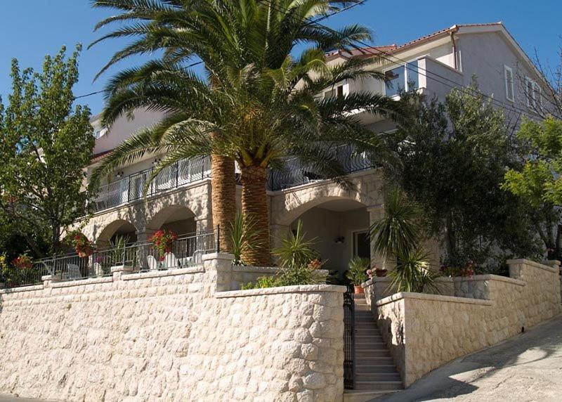 a house with a palm tree in front of it at Apartments Marco Polo in Rab