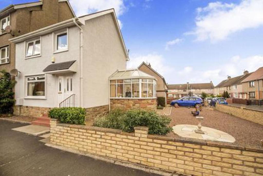 a house with a brick wall in a parking lot at Beautiful three bedroom seaside retreat in Prestonpans