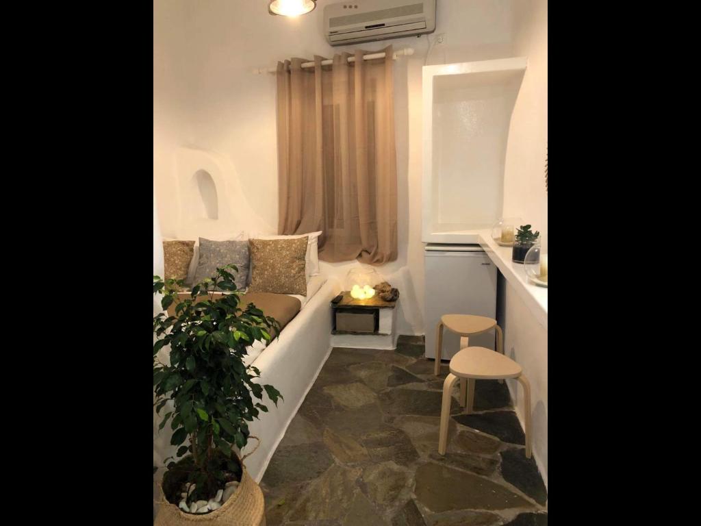 een kleine woonkamer met een bank en een plant bij Amarielia's Studios in Tinos Town