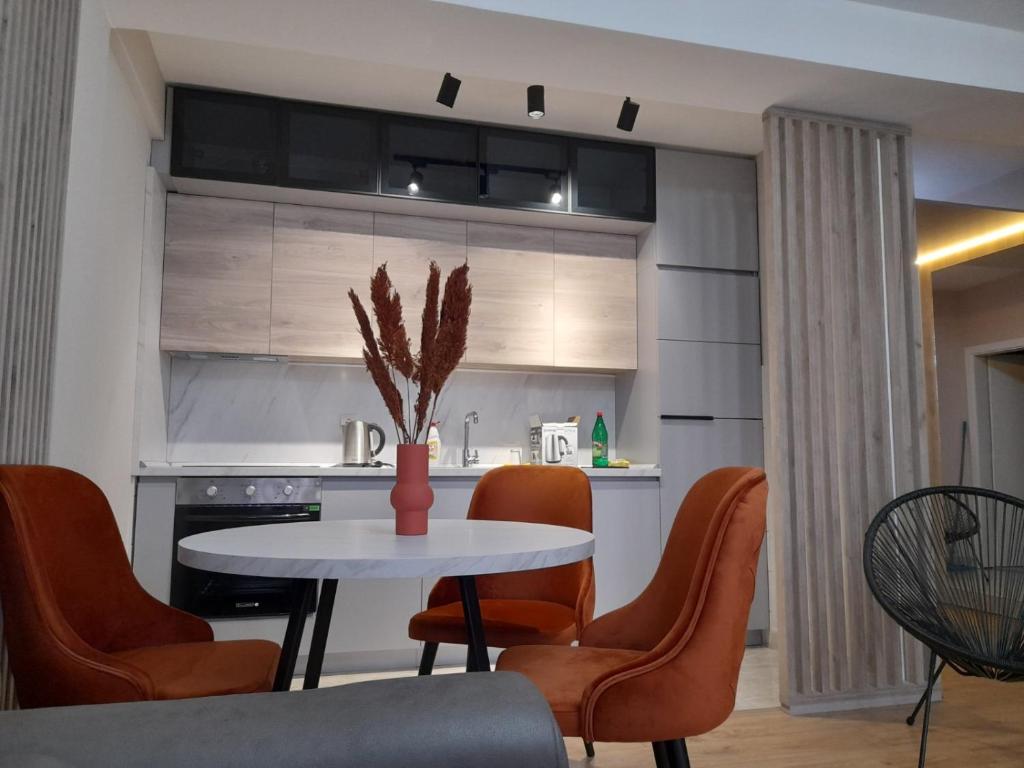 a kitchen with a table with orange chairs and a kitchen at Centar two apartment in Skopje