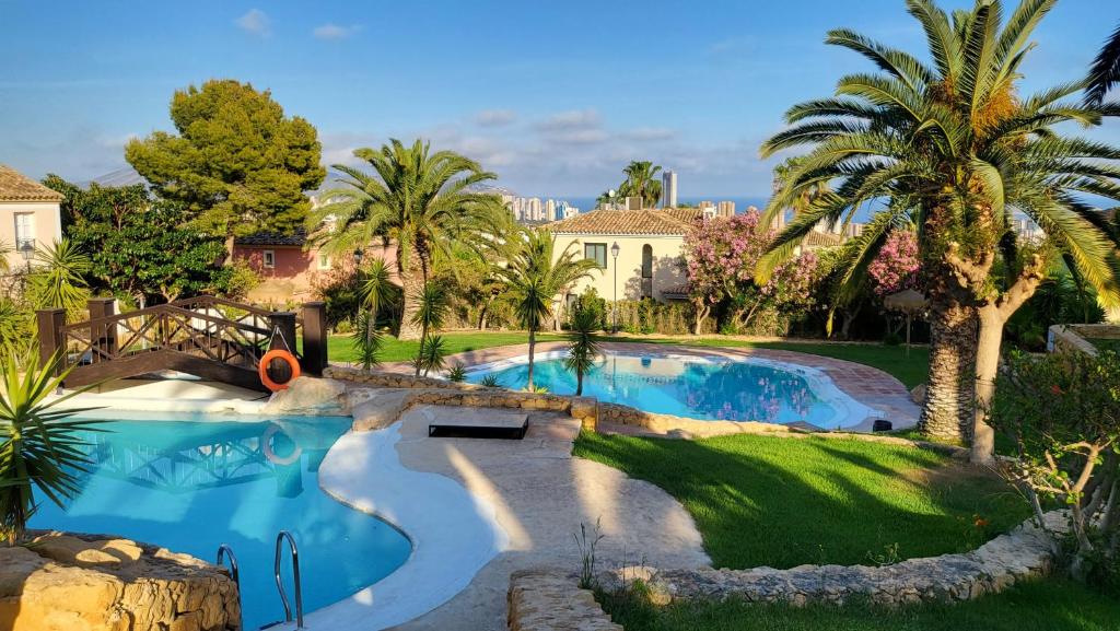 a swimming pool in a yard with palm trees at Casa Maia - cosy holidays in Benidorm in Cala de Finestrat