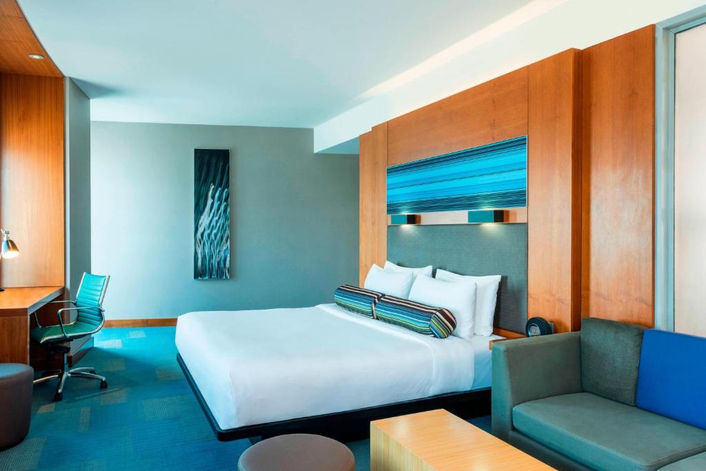een slaapkamer met een bed, een bureau en een bank bij Aloft Abu Dhabi in Abu Dhabi