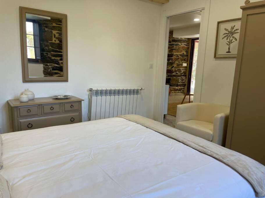 a bedroom with a large white bed and a chair at Moderno apartamento con jardín in Santa María La Mayor del Rosario