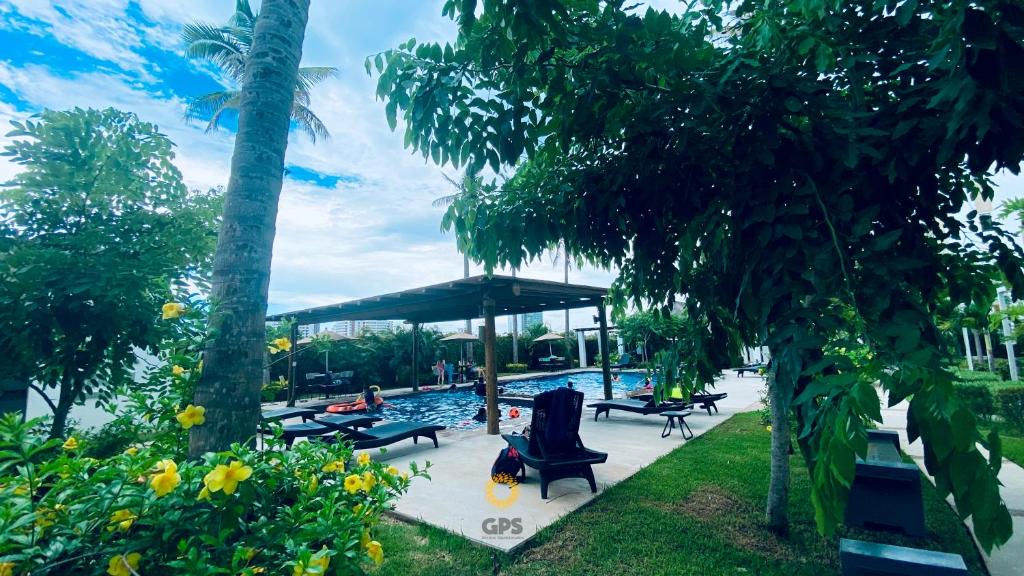 una piscina con sillas, sombrilla y árboles en Almar 303 en Cerritos cerca de la playa!, en Mazatlán