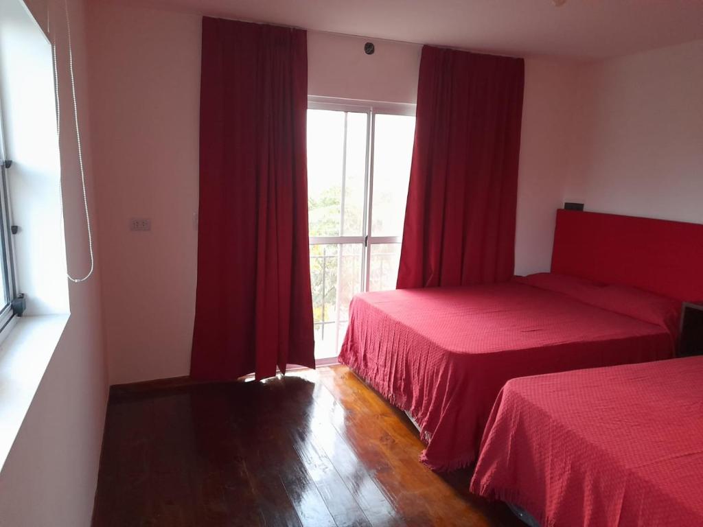 a bedroom with two beds and a window with red curtains at Mirador de Estrellas in Tupungato