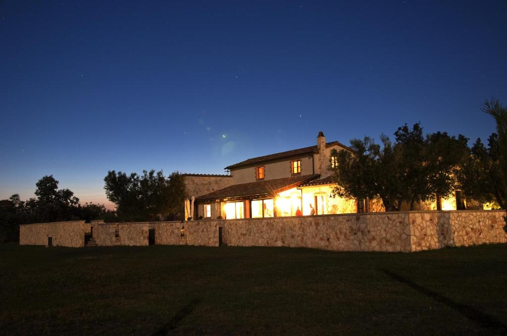a house with a stone wall at night at Agriturismo Lupo Cerrino in Tarquinia