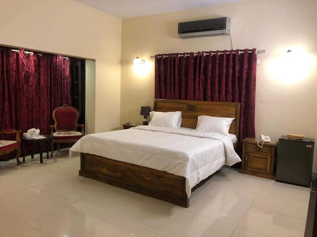 a bedroom with a large bed and red curtains at Hotel Inn Karachi in Karachi