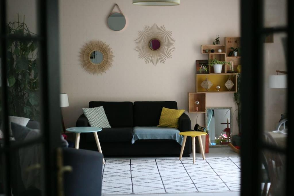 uma sala de estar com um sofá preto e duas mesas em Grand et charmant appartement familial, 3 chambres, et moderne avec grand jardin et parking privatif aux portes de Paris em La Garenne-Colombes