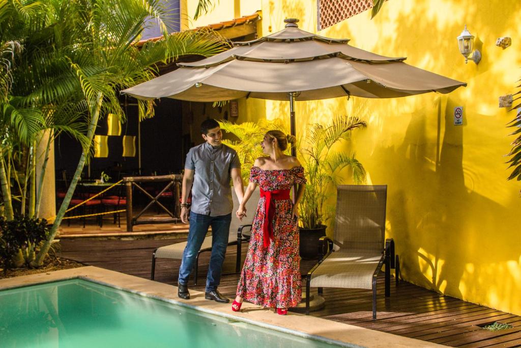 a man and a woman standing next to a swimming pool at Hotel Marionetas in Mérida