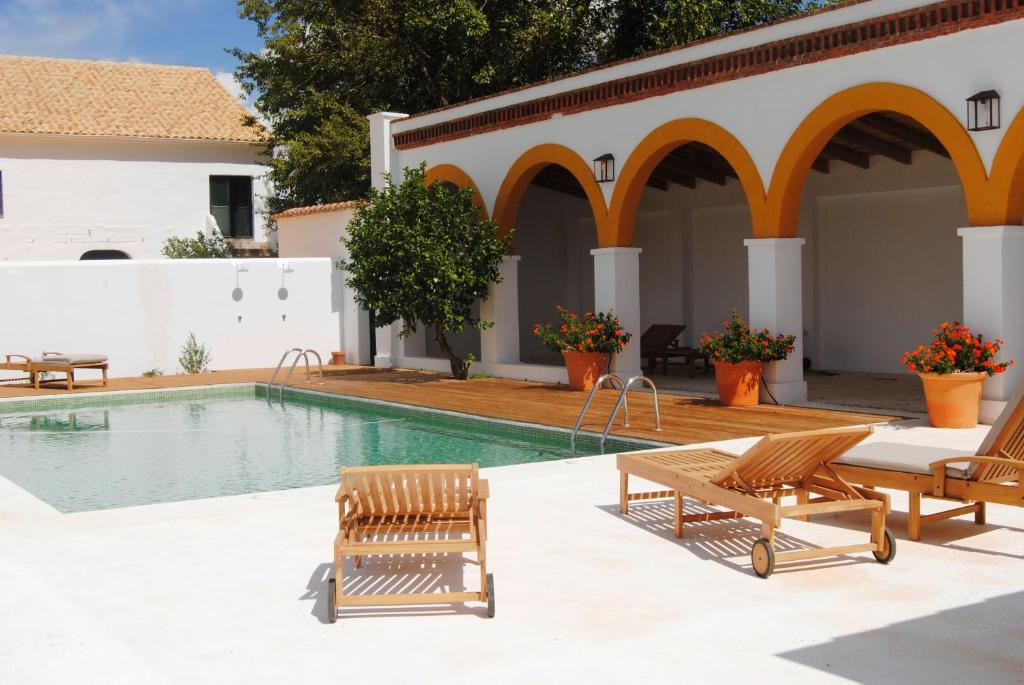 a swimming pool with two lounge chairs next to a building at Cortijo de Vega Grande in Llerena