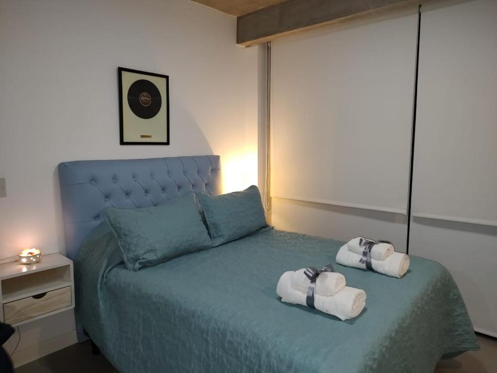 Un dormitorio con una cama azul con toallas. en Palermo Scent 2 en Buenos Aires