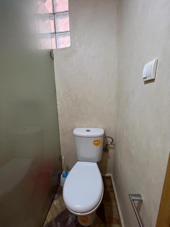 a bathroom with a white toilet and a window at Dar diafa samira in Mirleft