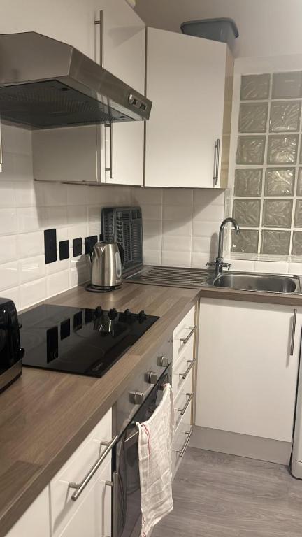 La cuisine est équipée de placards blancs et d'un four avec plaques de cuisson. dans l'établissement Flat 1, à Hendon