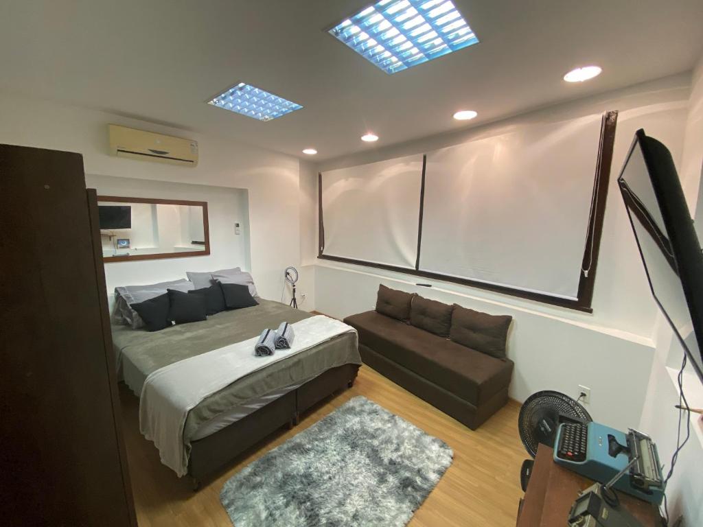 ein Schlafzimmer mit einem großen Bett und einem Sofa in der Unterkunft Vai ser feliz in Rio de Janeiro