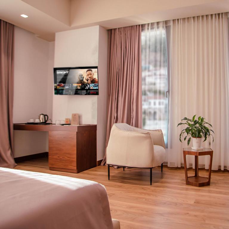 um quarto de hotel com uma cama e uma cadeira e uma televisão em Portik Hotel em Berati