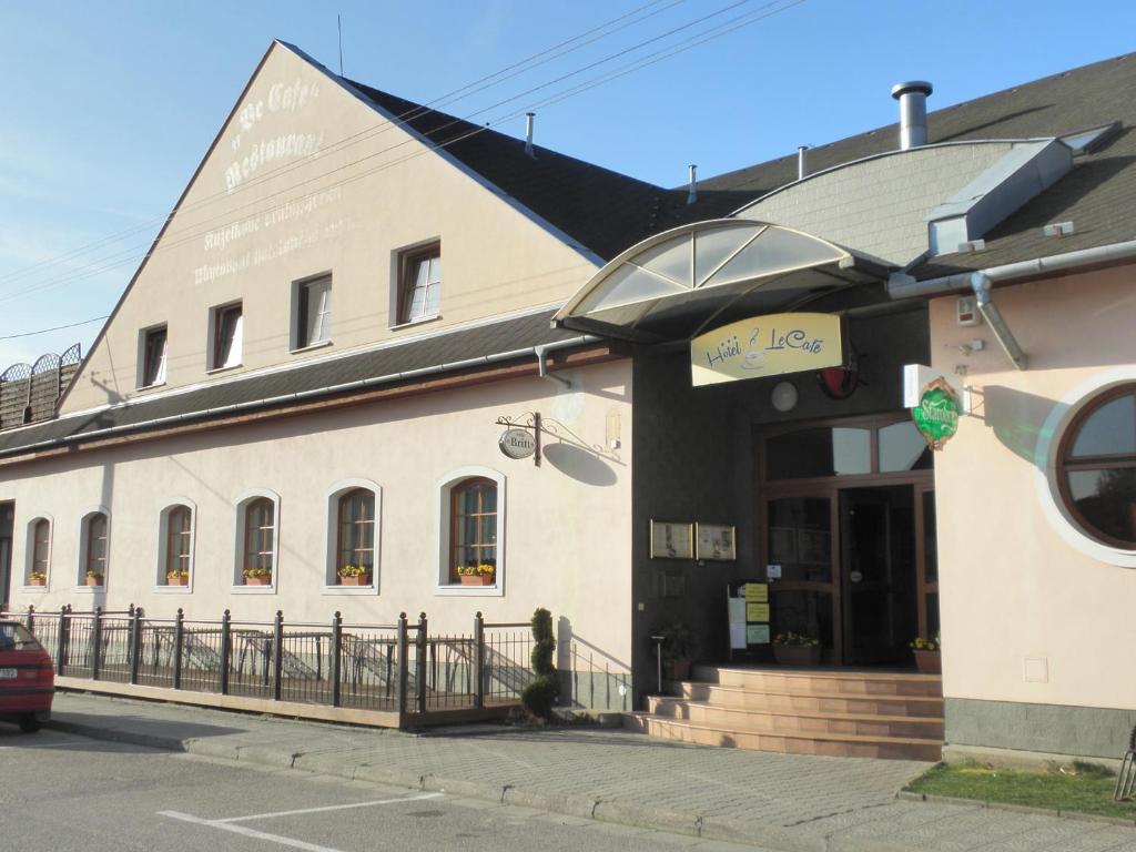 duży biały budynek po stronie ulicy w obiekcie Hotel Le Café w mieście Pohořelice