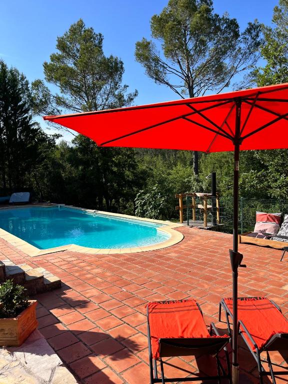 un parapluie rouge assis à côté d'une piscine dans l'établissement Natur & Jasmin Chambres d'hôtes naturistes en Provence, à Lorgues