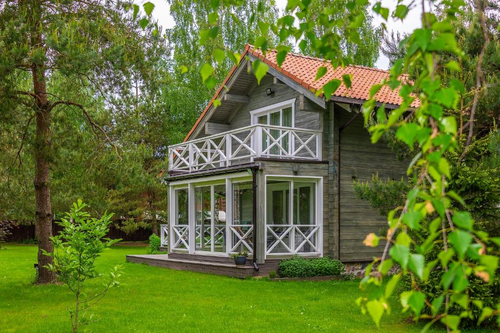 een klein huis met een veranda op een groen gazon bij Vila Shakti in Rudžionys