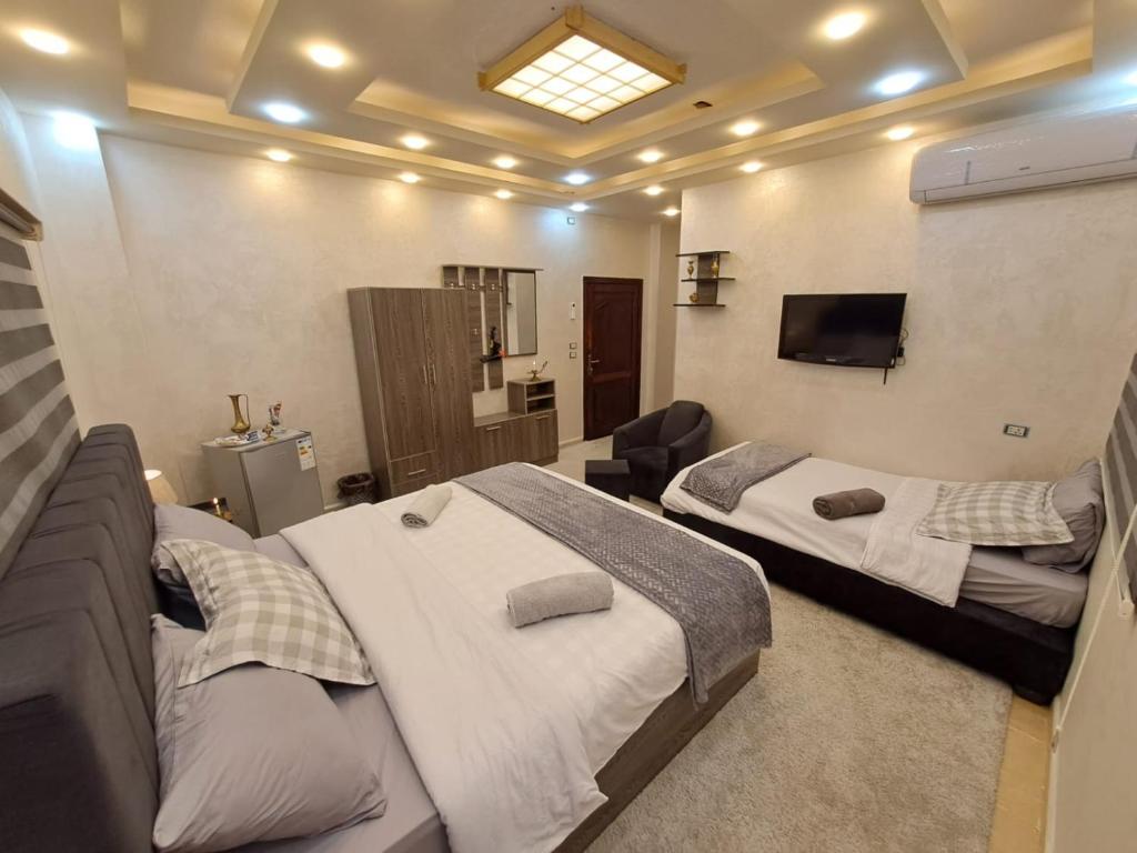 a bedroom with two beds and a flat screen tv at Hadrian's Arch in Jerash