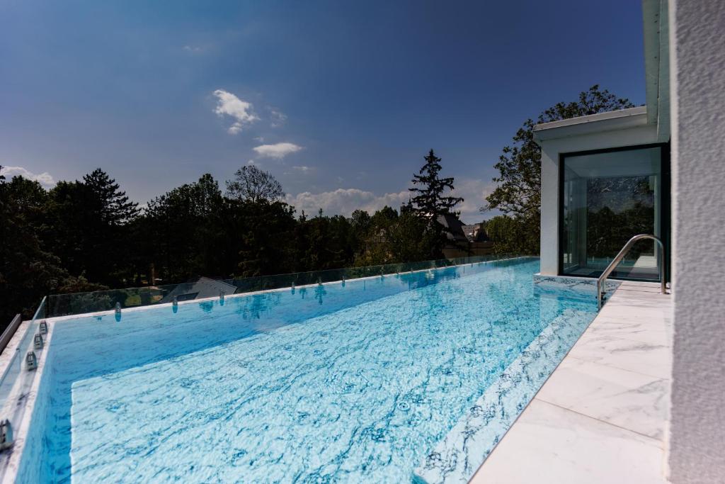 a large swimming pool with blue water at Villa Bauhaus Wellness Apartman Fsz. 3 in Siófok