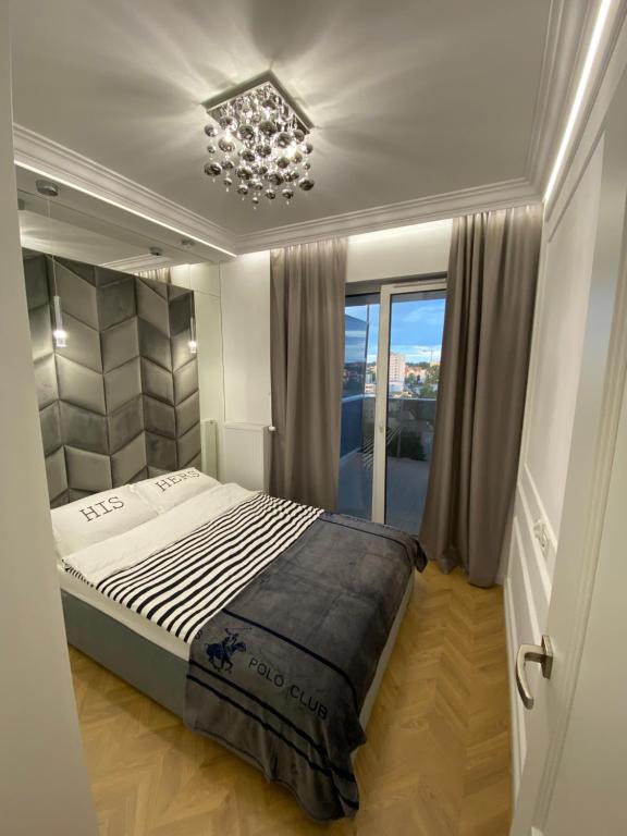 1 dormitorio con cama y lámpara de araña en Apartamenty Jagiellońskie Jurowiecka 15, en Białystok